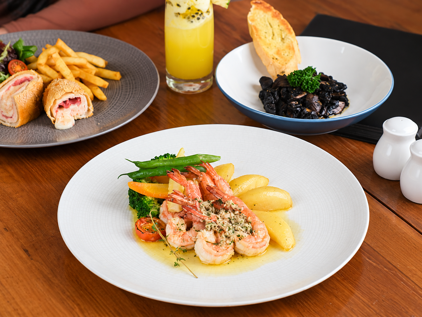 Gourmet shrimp dish served with vegetables, fries, and refreshing drinks.