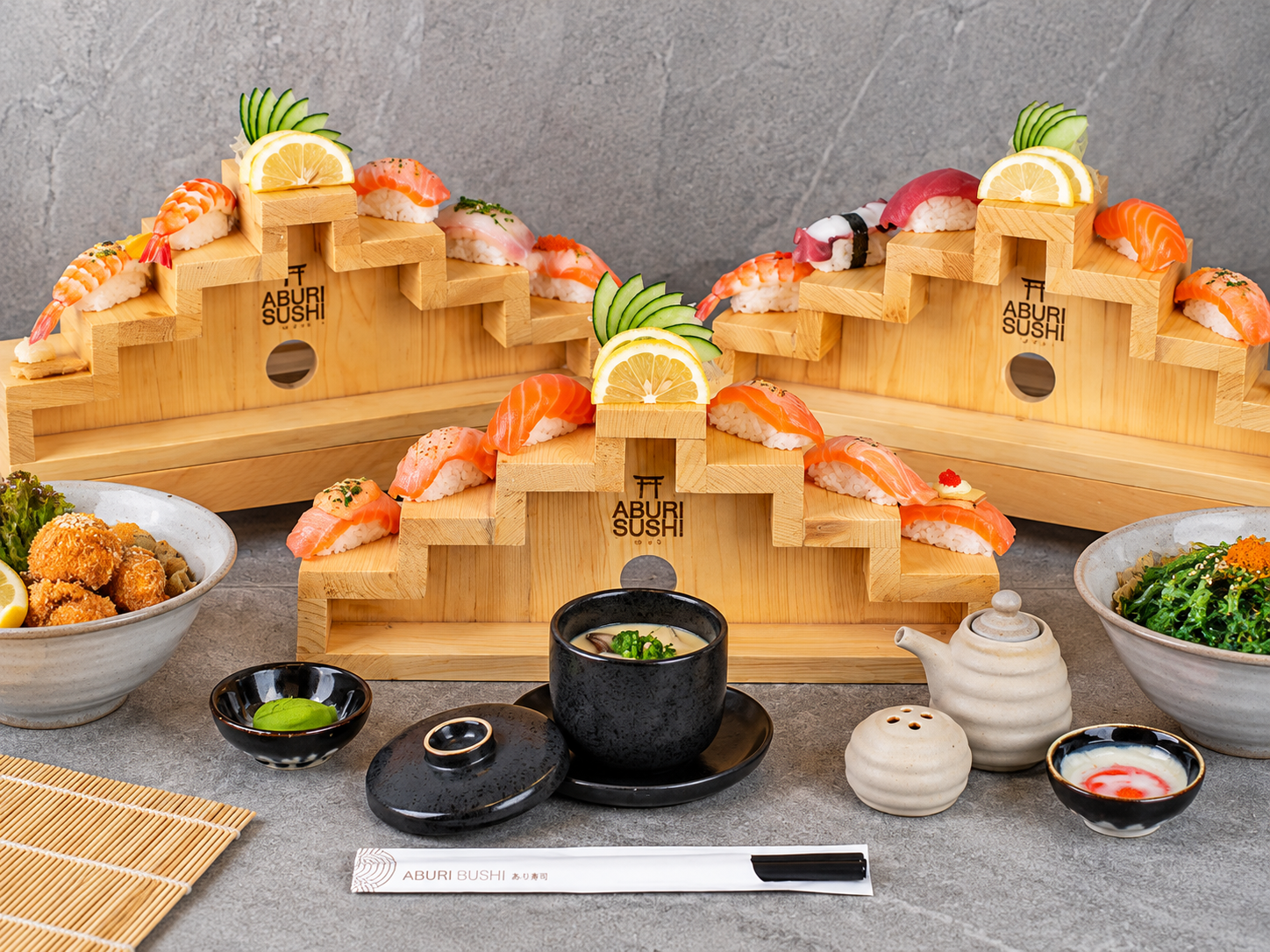 Aburi sushi rolls arranged on a wooden staircase platter with fresh garnishes.