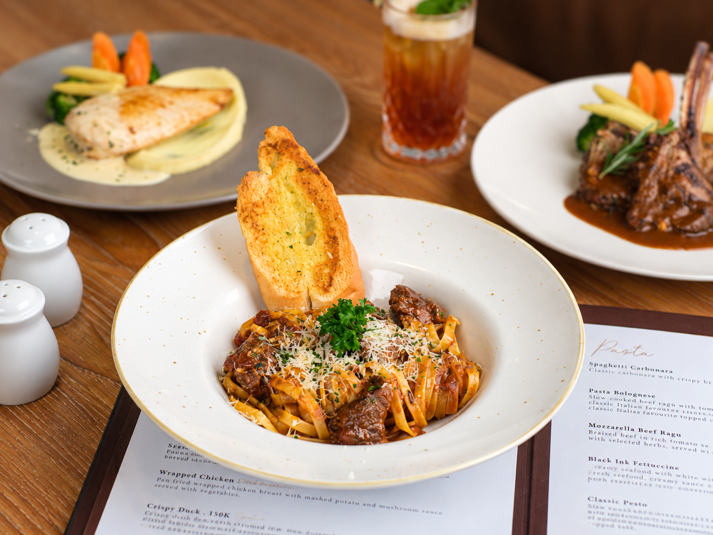 Pasta ragù served with toasted garlic bread and iced tea.
