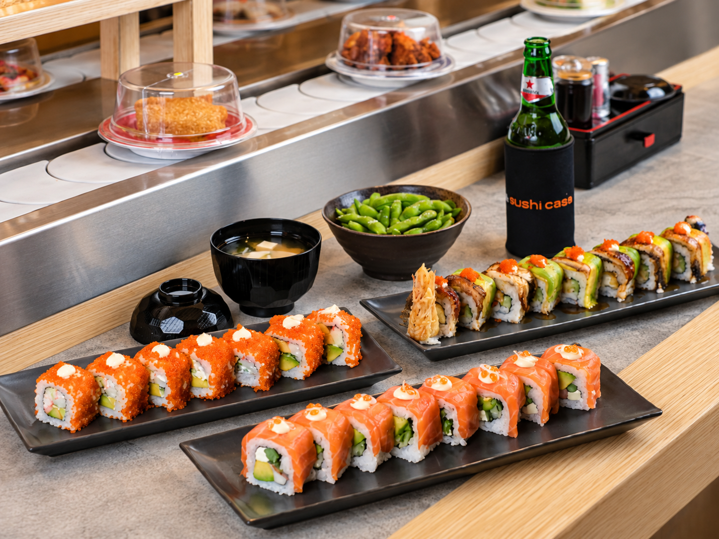 Assorted sushi rolls and Japanese dishes displayed on a conveyor belt.