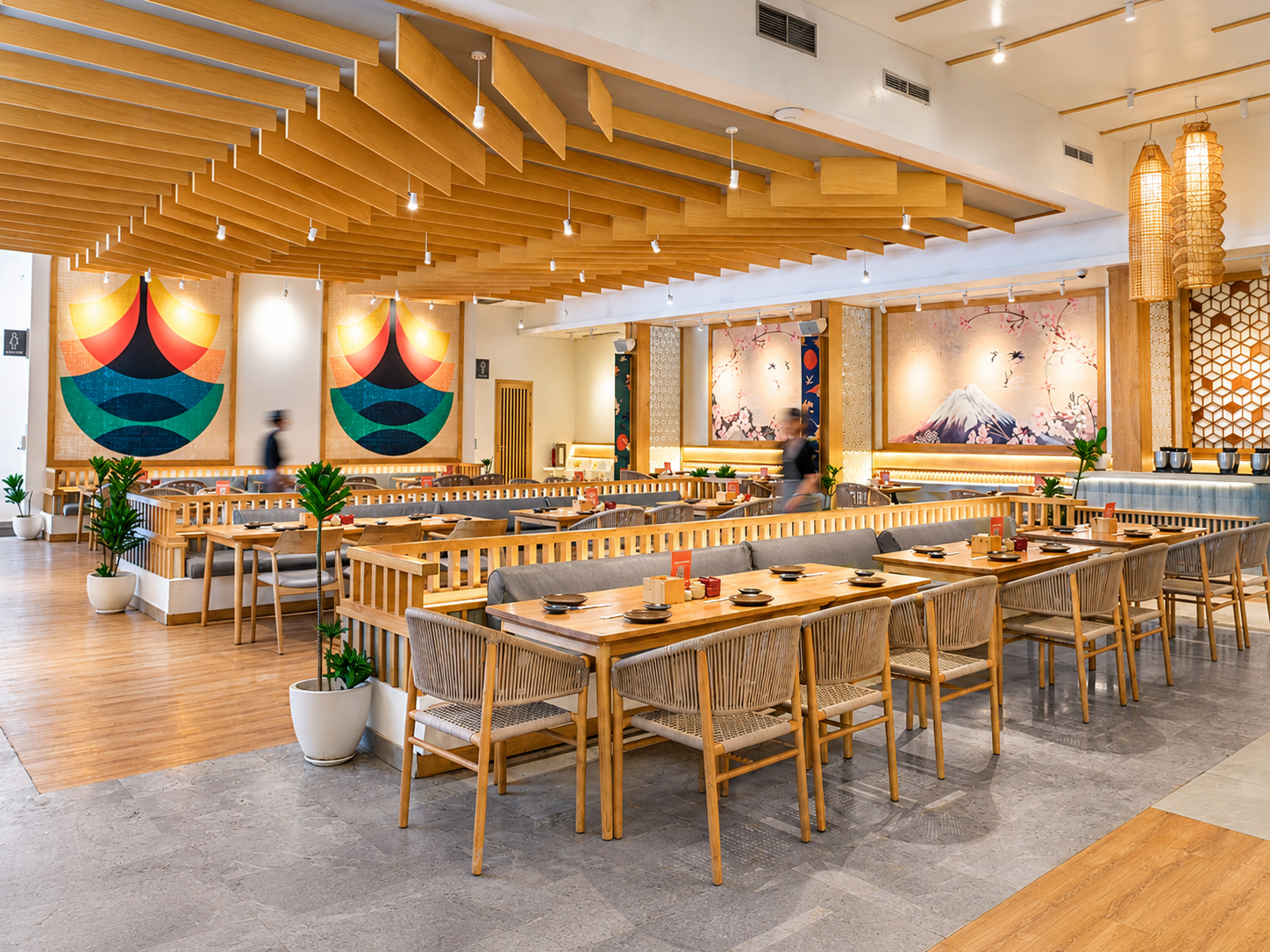 Modern Japanese-inspired restaurant dining hall with wooden ceiling beams and a sushi counter.