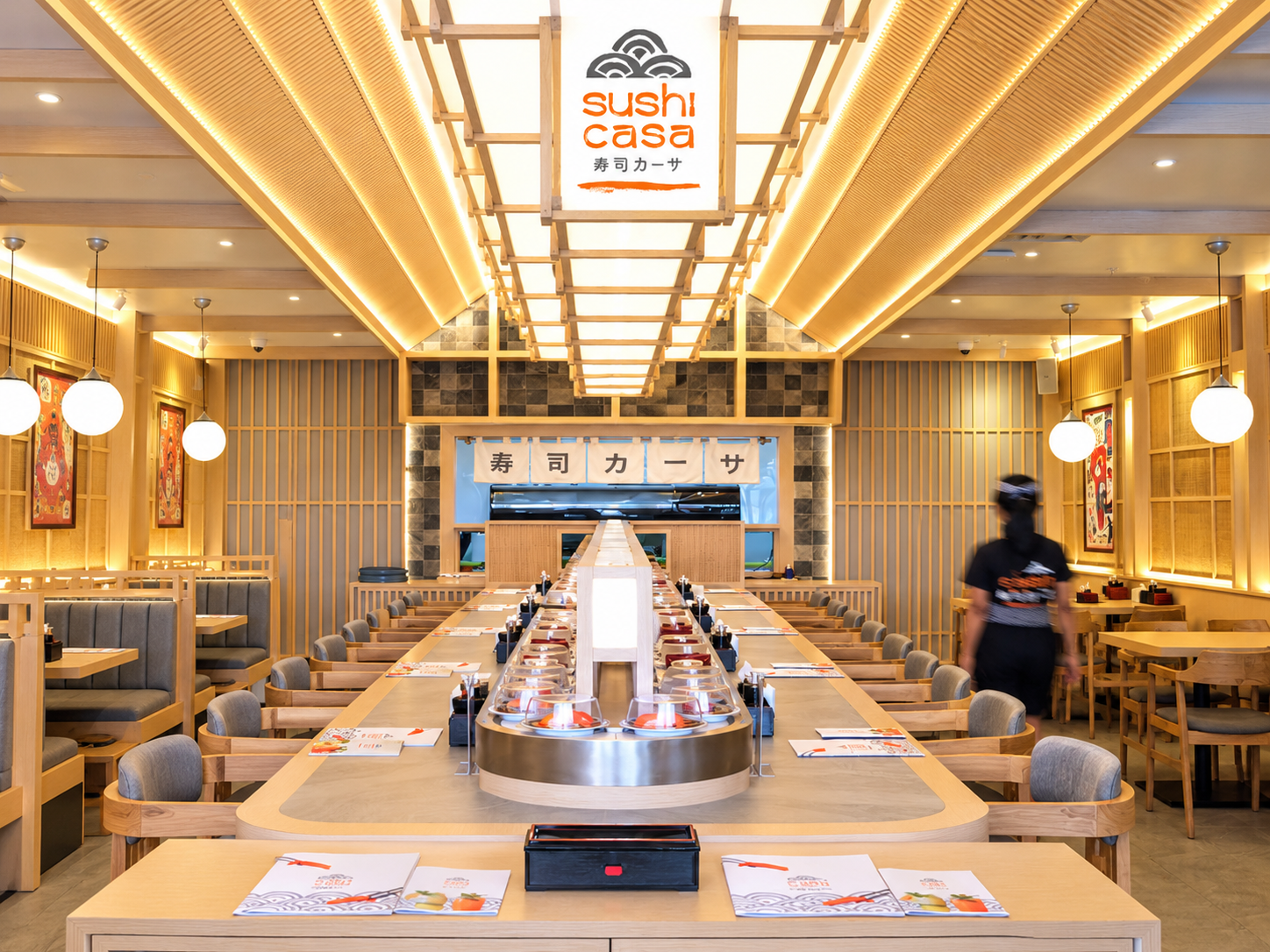 Modern Japanese sushi restaurant interior with warm lighting and a central sushi counter.